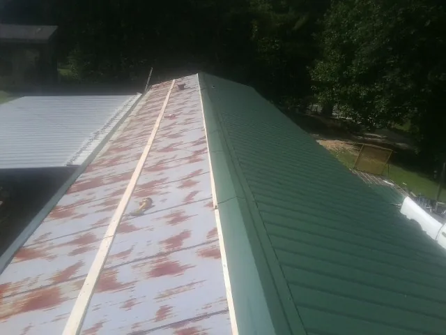 Old rusted panels beside newly installed green metal roofing — Wind Damage Roof Repair by Roofing Brothers in East Stone Gap