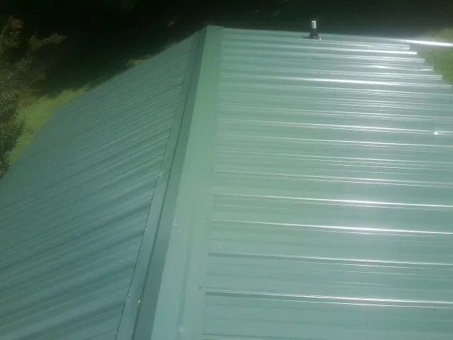 New green metal panels meeting at the ridge of a roof — Flat Roof Repair work by our crew in East Stone Gap