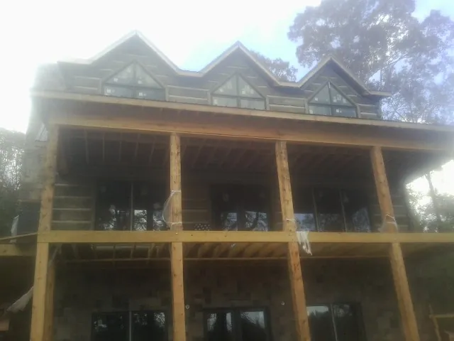 Dormers and porch framing on a large log home under construction — Roof Coating work by our crew in East Stone Gap