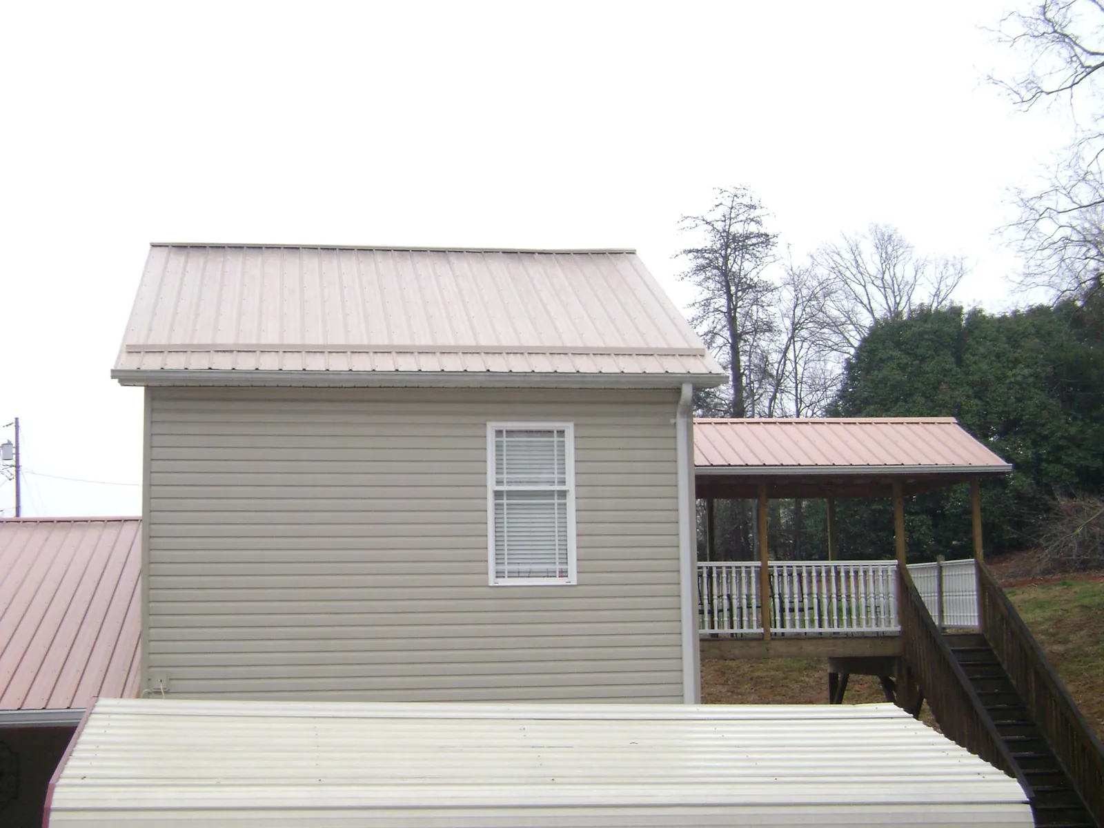 Tan metal roofs on a two story addition and attached porch, from a Roof Replacement job in East Stone Gap