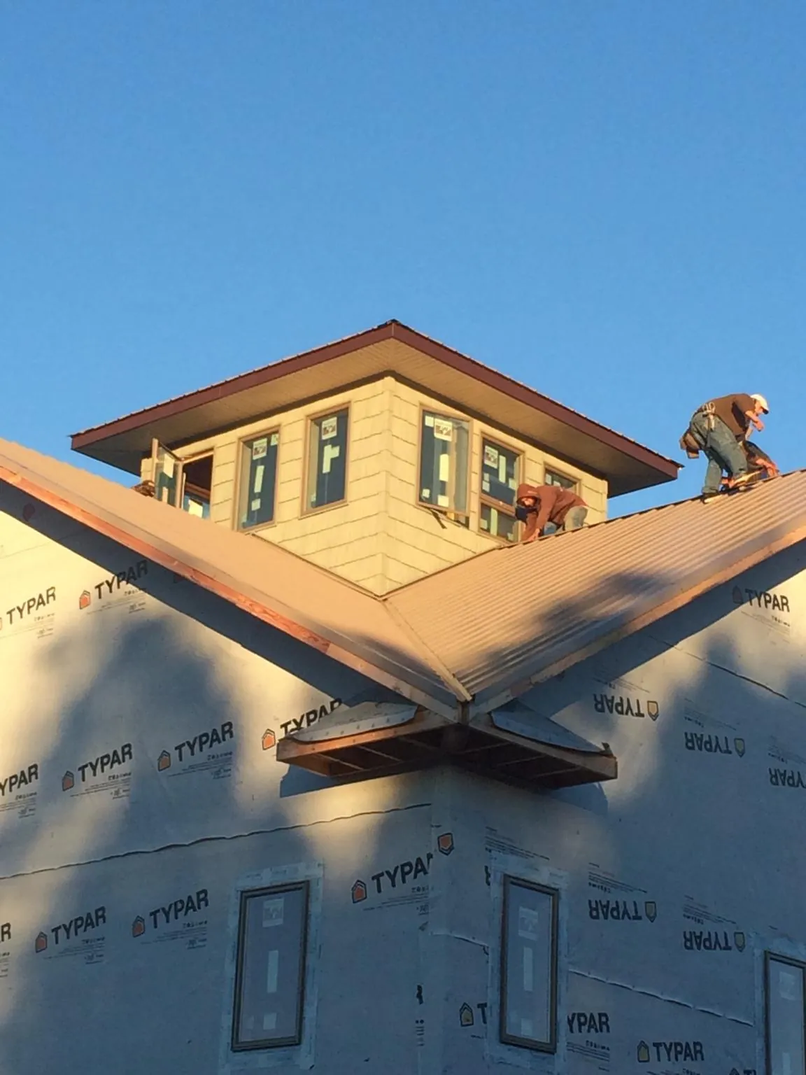 Roofers working around a rooftop cupola on a new metal roof at sunset — Roof Waterproofing in East Stone Gap by Roofing Brothers